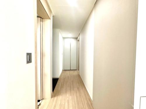 a hallway with white walls and wooden floors at The November Stay Guri Station in Guri