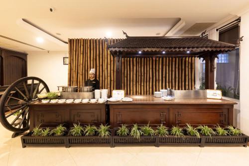 a chef is standing behind a kitchen with a cart at Khemara Angkor Hotel & Spa in Siem Reap