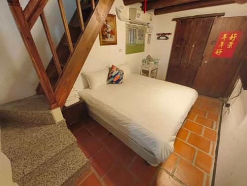 a small room with a bed and a staircase at 湖峰古厝民宿 in Jinning