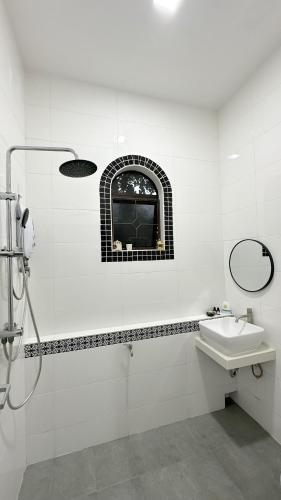 a white bathroom with a sink and a window at The Manzil Janda Baik in Bentong