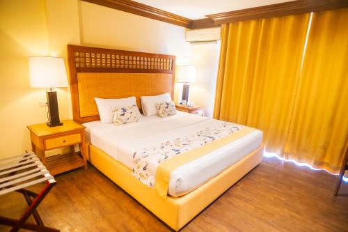 a bedroom with a large bed and yellow curtains at Boracay Tropics Resort Hotel in Boracay