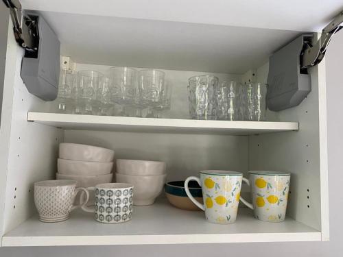 a shelf with cups and mugs in a cabinet at SPA Relax 3 chambres in Saint-Joseph