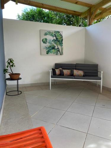 a patio with a bench and a painting on the wall at SPA Relax 3 chambres in Saint-Joseph