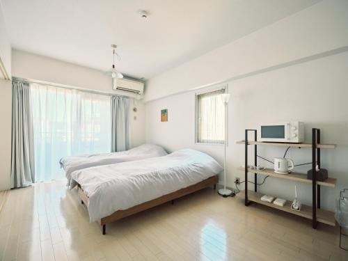 a bedroom with two beds and a television in it at vetta kumamoto shinyashiki 701 in Kumamoto