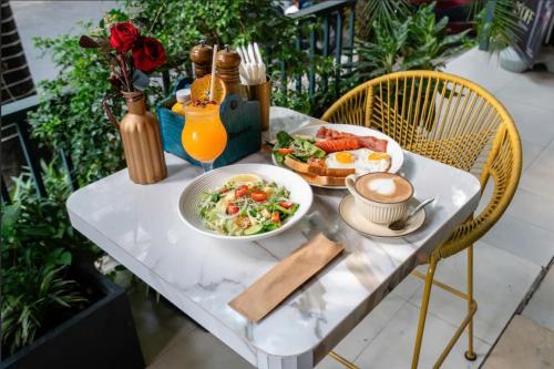 a table with a plate of food and a bowl of salad at La Bonita Hotel and Apartments in Ho Chi Minh City