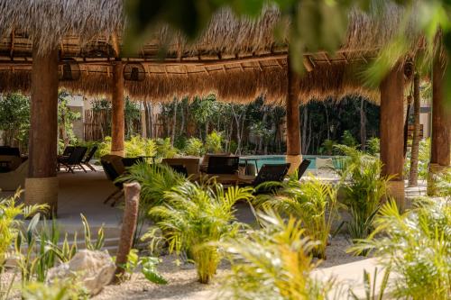 a restaurant with a straw umbrella and chairs and plants at Luxury Jungle Condos by Casago in Tulum