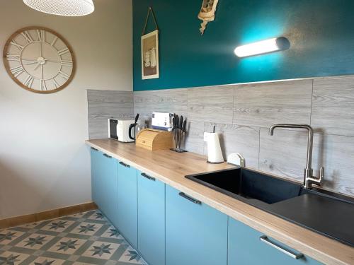 une cuisine avec un évier et une horloge murale dans l'établissement Maison rénovée avec jardin, proche plage et commerces – Capacité 6 personnes - FR-1-323-511, à Saint-Hilaire-de-Riez