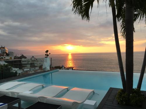 einen Pool mit Sonnenuntergang über dem Meer in der Unterkunft DTerrace Luxe 2bd 2ba Romantic Zone Los Muertos Beach and Pier in Puerto Vallarta