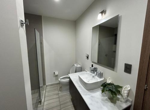 a bathroom with a sink and a toilet and a mirror at Altomare Depa 1804 in Mazatlán