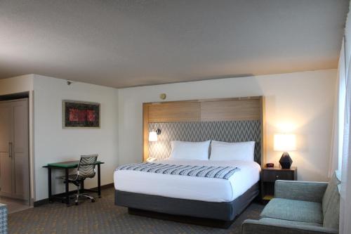 a hotel room with a large bed and a desk at Wyndham Flint MI Grand Blanc Bishop Airport Conference Ct in Flint