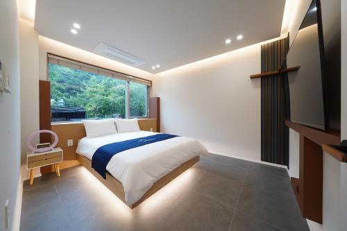 a bedroom with a bed and a large window at Gyeongju Poolvilla Runtoyou in Gyeongju