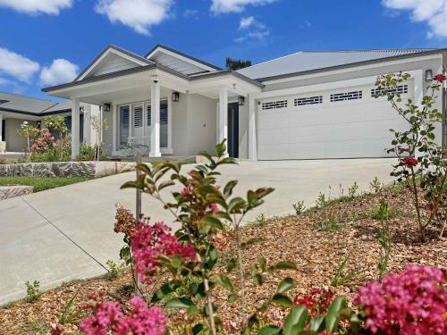 a white house with a driveway and flowers at Vue 47 in Nulkaba