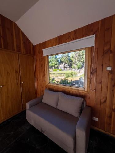 a small couch in a room with a window at Arrayan Lake View Mountain Lodge & Casa De Te Arrayan in San Martín de los Andes