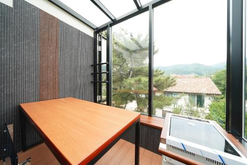 a balcony with a wooden table and a large window at Gyeongju Poolvilla Runtoyou in Gyeongju