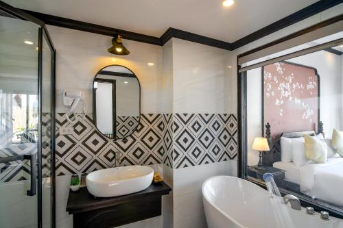 a bathroom with a tub and a sink and a mirror at Luang Prabang Vang Luang Hotel in Luang Prabang