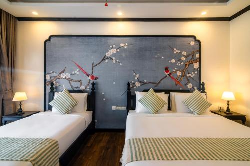 two beds in a room with a painting on the wall at Luang Prabang Vang Luang Hotel in Luang Prabang