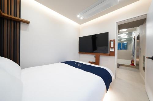a white bedroom with a bed and a flat screen tv at Gyeongju Poolvilla Runtoyou in Gyeongju