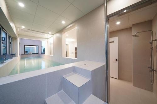 a bathroom with a swimming pool and a bath tub at Gyeongju Poolvilla Runtoyou in Gyeongju