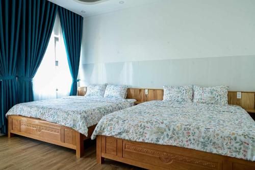 two beds in a bedroom with blue drapes at Căn Hộ 4 PN Rin's House Homestay in Phan Thiet