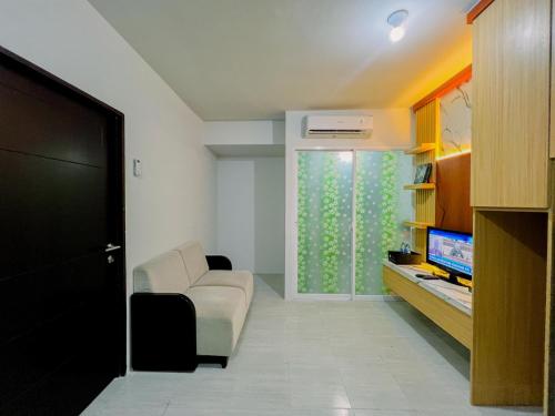 a living room with a couch and a television at Compact and Relaxing 2BR at Suncity Residence Apartment By Travelio in Sidoarjo