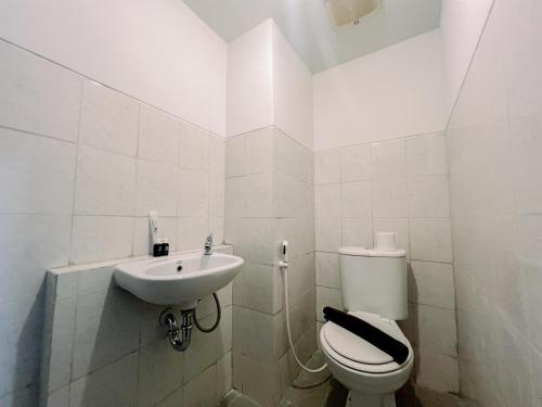 a white bathroom with a toilet and a sink at Compact and Relaxing 2BR at Suncity Residence Apartment By Travelio in Sidoarjo