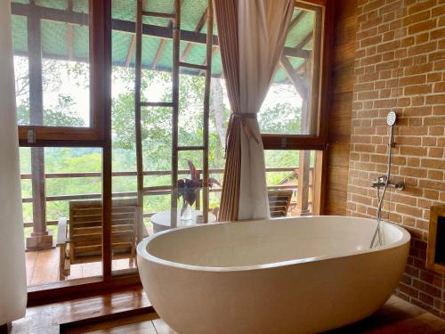 eine große weiße Badewanne in einem Zimmer mit Fenstern in der Unterkunft Sang Tirta Resort in Penebel