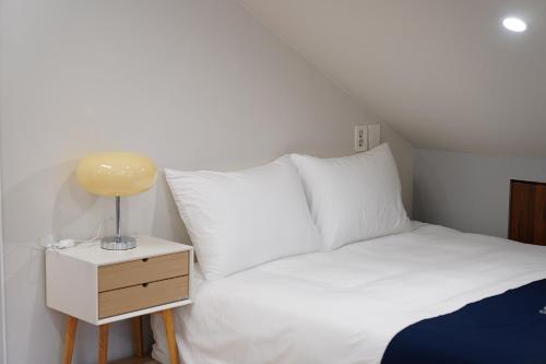 a bed with white sheets and a lamp on a night stand at Gyeongju Poolvilla Runtoyou in Gyeongju