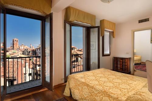 Royal San Marco Hotel في البندقية: غرفة نوم بسرير وشرفة مطلة
