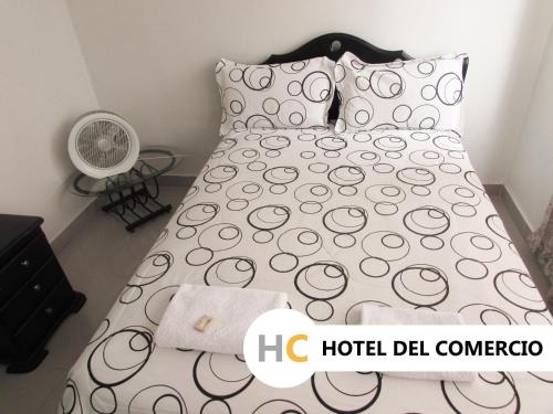 Cama con colcha y almohadas blancas y negras en Hotel del Comercio, en Villavicencio