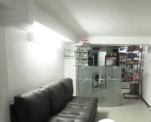 a living room with a leather couch and a refrigerator at Hotel del Comercio in Villavicencio