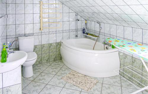 a bathroom with a tub and a toilet and a sink at Nice Home In Lidzbark Warminski in Lidzbark Warmiński