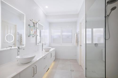 a white bathroom with two sinks and a shower at Canal living 3 bed or 1 bed with Pool in Redcliffe