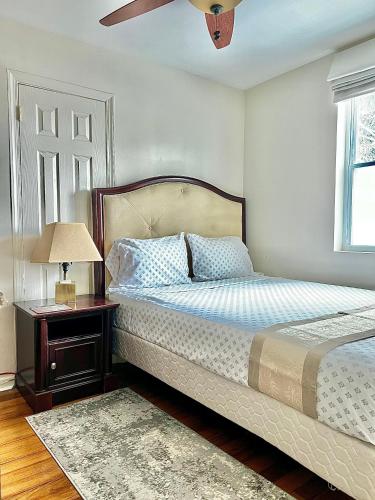 a bedroom with a bed and a table with a lamp at Aloha Homestay Falls Church in Falls Church