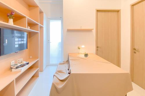 a room with a bed and a flat screen tv at Good and Cozy Stay 2BR Tokyo Riverside PIK 2 Apartment By Travelio in Tangerang