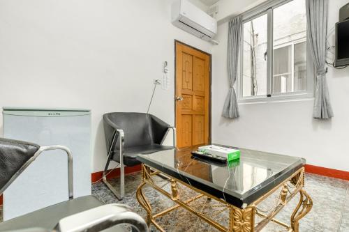 a living room with a glass table and a chair at Rich House B&B in Kenting