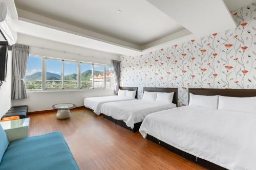 a room with three beds and a couch and windows at Rich House B&B in Kenting