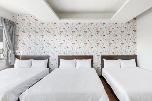 two beds in a room with a wall with flowers at Rich House B&B in Kenting