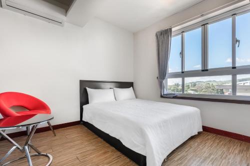 a bedroom with a bed and a red chair at Rich House B&B in Kenting