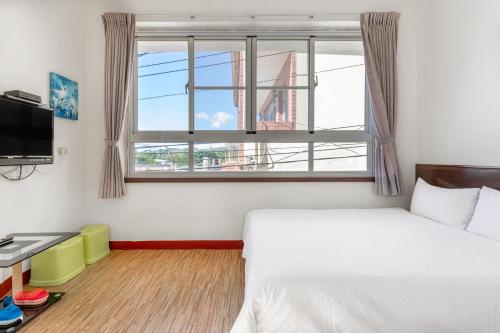 a bedroom with a bed and a large window at Rich House B&B in Kenting