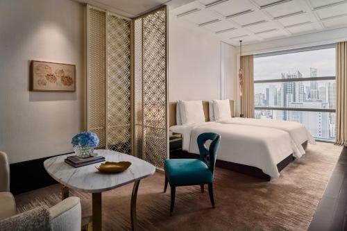 a hotel room with a bed and a table and a couch at Rosewood Bangkok in Bangkok