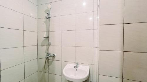 une salle de bain carrelée blanche avec douche et toilettes dans l'établissement Relaxing Studio No Kitchen Apartment Bandaraya Tallasa City Makassar By Travelio, à Paranglu