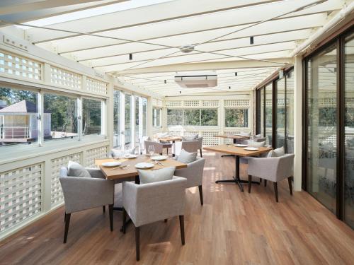 a dining room with tables and chairs and windows at アドベンチャーズアイランド 小谷流沢ロッジ in Yachimata