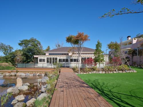 a house with a brick walkway in front of a pond at アドベンチャーズアイランド 小谷流沢ロッジ in Yachimata