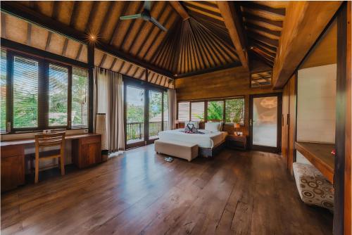 a bedroom with a bed and a desk and windows at Surya Kembar Villas in Ubud