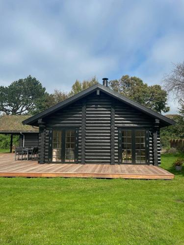 a log cabin with a deck in the grass at Nordic Exclusive Log House On The North Coast in Tisvildeleje