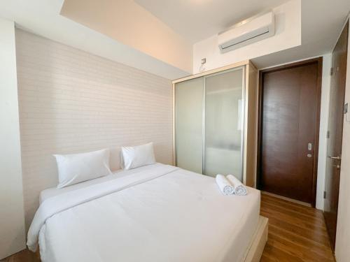 a bedroom with a white bed with two white shoes on it at Good Location and Serene 2BR at Linden Apartment By Travelio in Surabaya