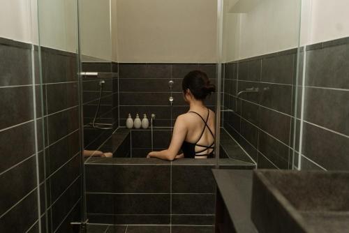 a woman sitting in a shower in a bathroom at Myeongjigak in Namwon
