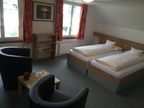 a hotel room with two beds and a chair at Gästehaus Sonne in Bütschwil