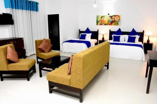 a hotel room with two beds and two chairs at Blue Spring Hotel Wadduwa in Wadduwa