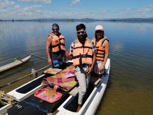 three people are standing on a boat in the water at My Home Guest in Polonnaruwa